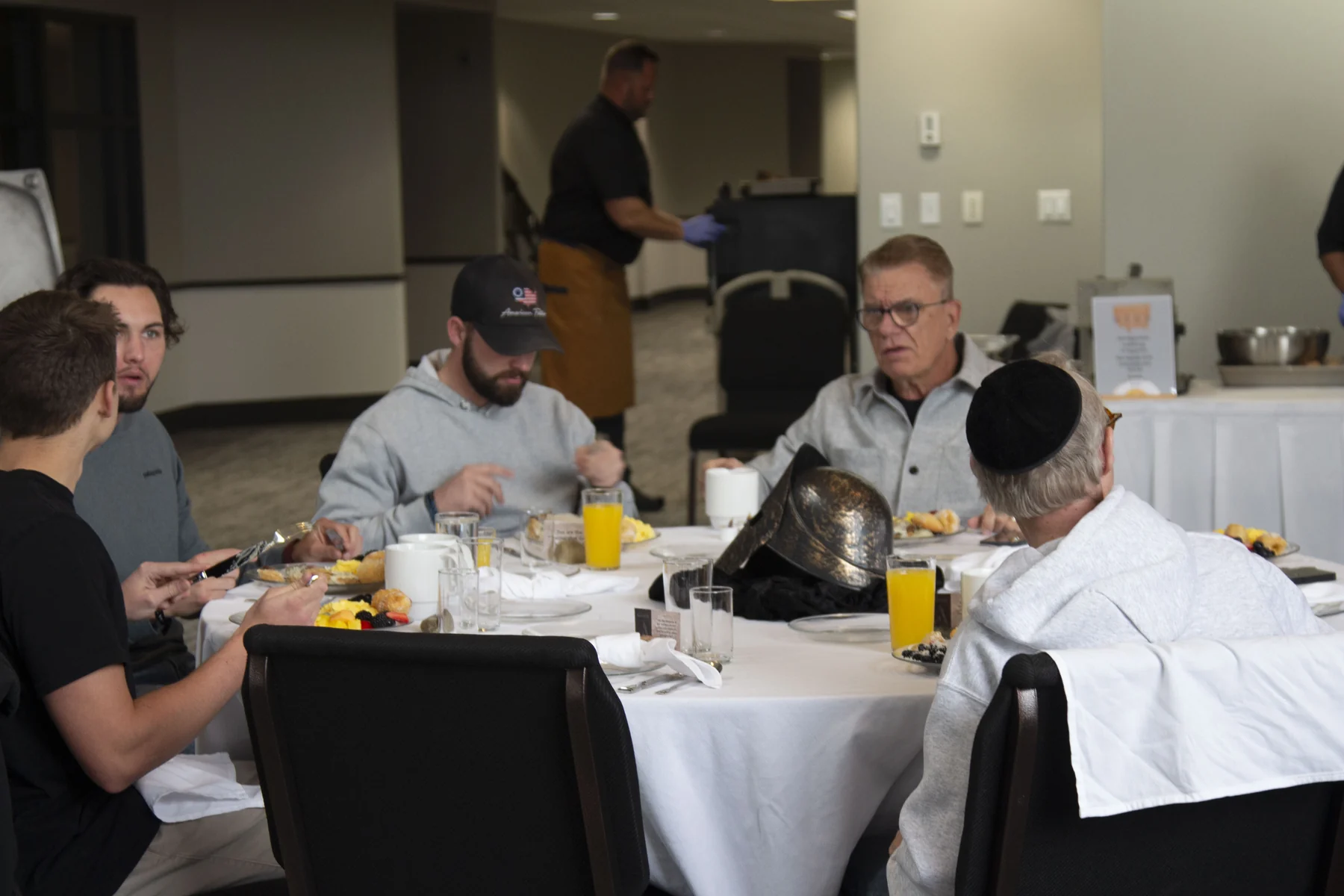 Group of people dining at a white-clothed table during an indoor business event
